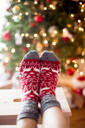 Close-up. Women's feet in Christmas socks near the Christmas tree. Holidays.の写真素材