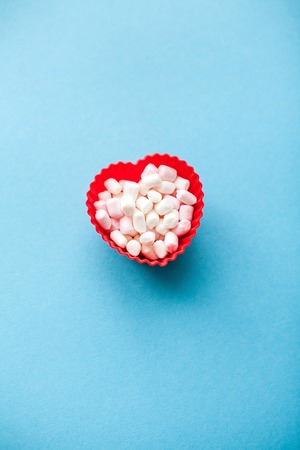 Red heart shape with marshmallows on a blue background. Valentine's Day. Love.の写真素材