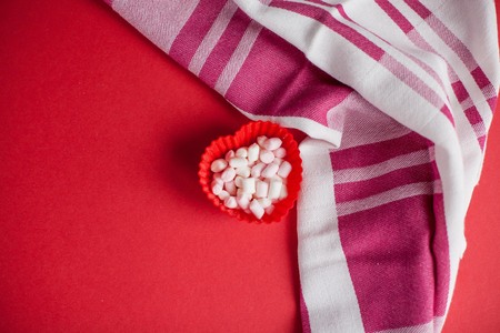 Valentine's day concept. Marshmallow, heart, kitchen towel on a red background.の写真素材