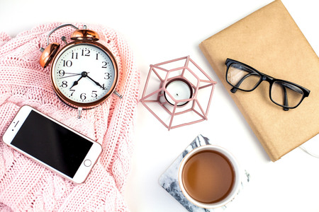 Spring decor. Women's clothing. Alarm clock, candle, tea mug, glasses, notebook on a white...