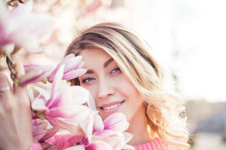 Spring portrait of a young blonde near a flowering tree. Happy young woman. Spring.の写真素材