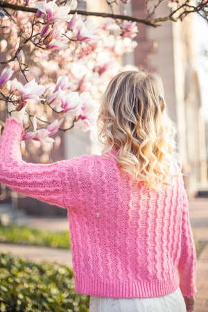 Spring portrait of a young blonde near a flowering tree. Happy young woman. Spring.の写真素材