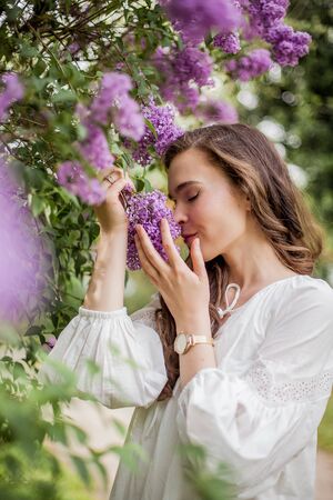 Portrait of a beautiful young woman near the blossoming lilac. Spring.の写真素材