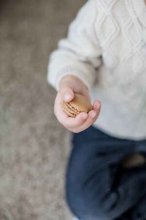 The boy holds macaroon in his hand. Autumn. Cozy.の写真素材