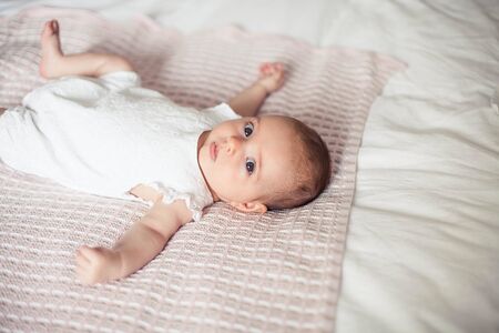 Little cute girl 3 months old is lying on the bed. Baby. Children bedroom.の写真素材