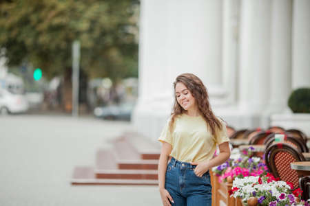A beautiful young woman of 16 years old stands near a French cafe. Tourism. flowers.