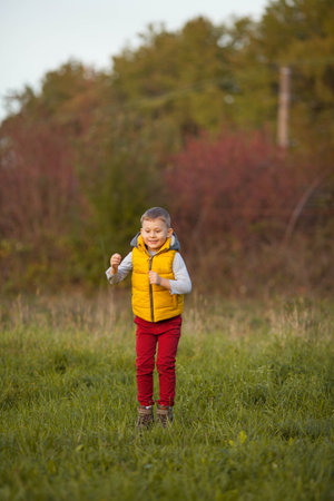 Little cute boy 5 years old walks in the autumn garden. Portrait of a happy boy in bright, autumn clothes.の写真素材