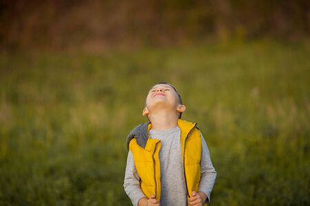 Little cute boy 5 years old walks in the autumn garden. Portrait of a happy boy in bright, autumn clothes.の写真素材
