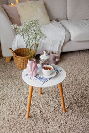 Spring home cozy interior. A bouquet of flowers in a vase, a cup of tea, decor on a coffee table. Mood.の写真素材
