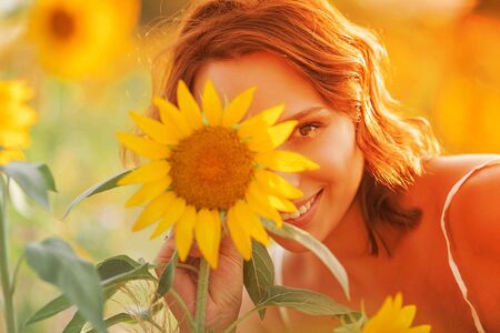 Beautiful young woman in the sunflower field. Portrait of a young woman in the sun. Summer.の写真素材