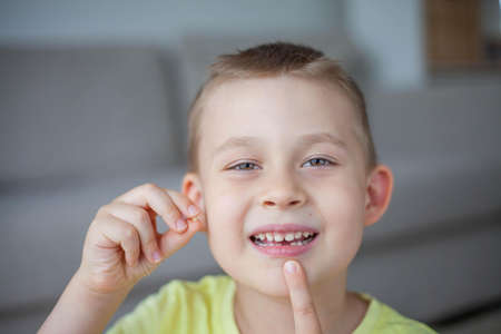 The child dropped the first milk tooth. Happy little boy and milk tooth. Boy.