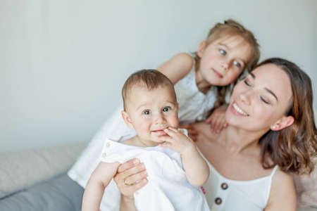 Young happy mother with her daughters in the home interior. Mothers Day. Cozy.