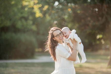 Young beautiful family walks in the park. Family portrait in the sunset light. Summer picnic. Spring.の写真素材