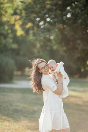 Young beautiful family walks in the park. Family portrait in the sunset light. Summer picnic. Spring.の写真素材