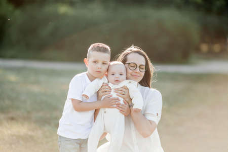 Young beautiful family walks in the park. Family portrait in the sunset light. Summer picnic. Spring.の写真素材