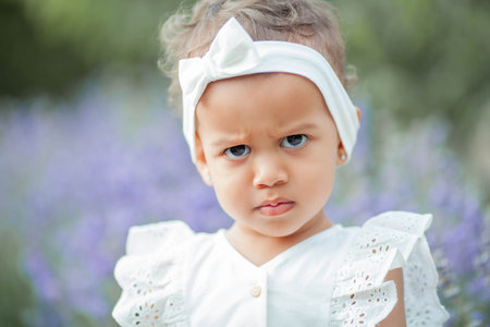 Beautiful young mother and her little daughter in blooming lavender. International family. Portrait of a beautiful little girl in the sunset light.の写真素材