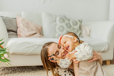 Happy mom and mulatto girl in home interior. Mothers Day. Baby.の写真素材
