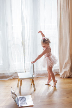Online classes. The little girl is engaged in ballet. Dancing. Home.の写真素材