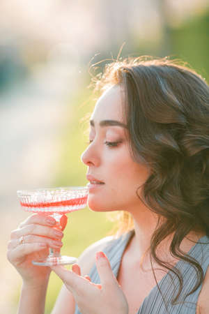 Beautiful young woman with curly hair is resting in the blooming sakura garden. Spring.の写真素材