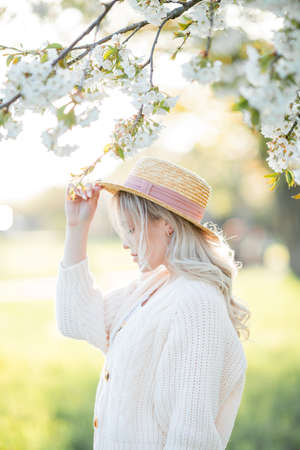 Beautiful young woman is resting on a picnic in a blooming garden. White flowers. Spring.の写真素材