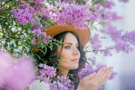 Portrait of a beautiful young woman in a blooming lilac park. Purple flowers. Spring.の写真素材