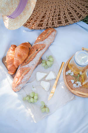 Outdoor picnic in a blooming garden. Wicker tray, cheese, pastries, fruits, on a blanket.の写真素材