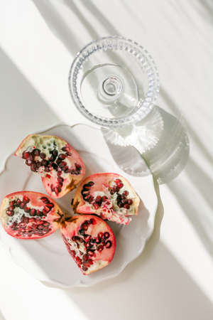 The background is white with shadows from a crystal glass, pomegranate.の写真素材