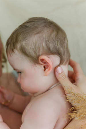Beautiful young mother with blue-eyed little daughter on a beige background.