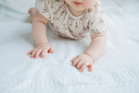 A cute little girl 5 months old lies on her stomach on the bed at home. Baby.の写真素材