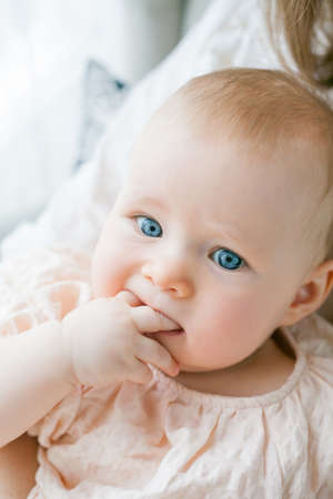 Happy young mother holds her little daughter 5 months old in her arms sitting in a chair at home.の写真素材