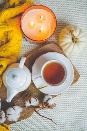 Autumn mood. A cup of hot cappuccino, pumpkins, knitted yellow plaid on a wooden stand. A branch of cotton. copy space. Cozy.の写真素材