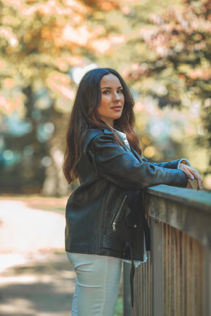 Young beautiful dark haired woman walks in the autumn park. Fall.