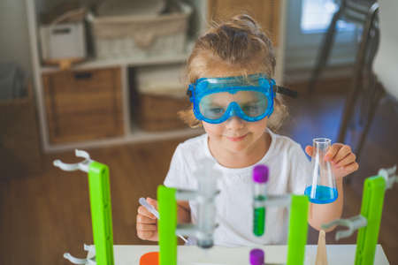 Science. Little cute girl sets up experiments at home, colored liquids, laboratory child's installation. School.の写真素材