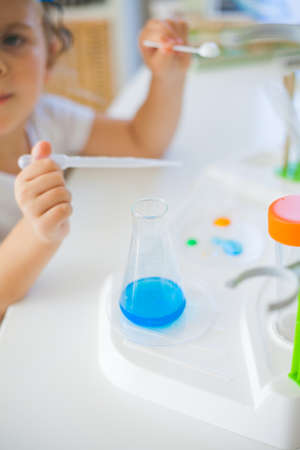Science. Little cute girl sets up experiments at home, colored liquids, laboratory child's...