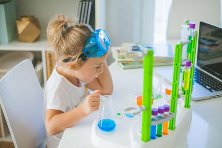 Science. Little cute girl sets up experiments at home, colored liquids, laboratory child's installation. School.の写真素材