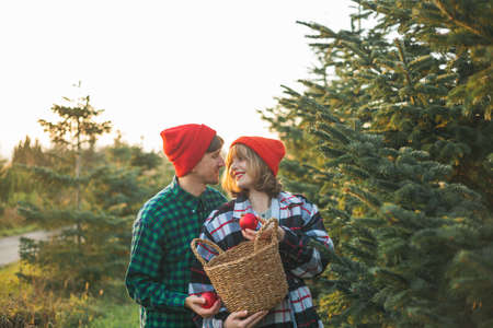 Christmas. Happy young couple in love in red hats and sweaters decorate Christmas tree.の写真素材