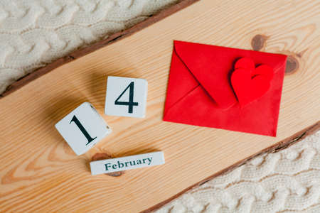 Valentine's day concept. Festive decor details. Red envelope and small valentine heart, wooden calendar on a wooden tray.の写真素材