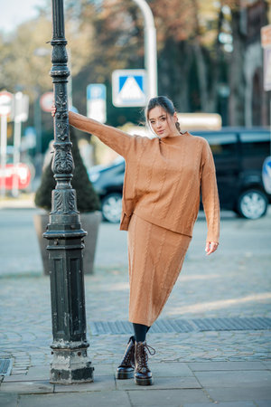 Stylish young woman in a warm suit in the city center. Beautiful model with dark long hair in autumn.の写真素材