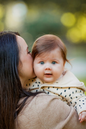 Beautiful young mother with a cute little girl 7 months old walks in the autumn park. Portrait of a...