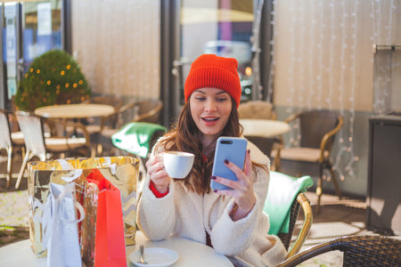 Young beautiful dark-haired women drinks coffee in a cafe and makes online purchases of Christmas gifts. winter holiday.の写真素材