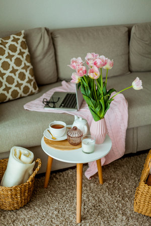 Home cozy office. Work at home. spring decor. Knitted blanket, bouquet of tulips, hot tea, laptop.の写真素材