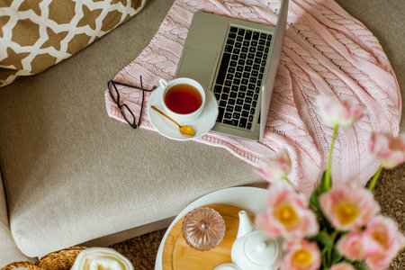 Home cozy office. Work at home. spring decor. Knitted blanket, bouquet of tulips, hot tea, laptop.の写真素材