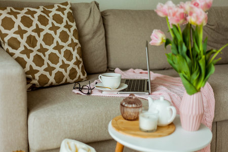 Home cozy office. Work at home. spring decor. Knitted blanket, bouquet of tulips, hot tea, laptop.の写真素材