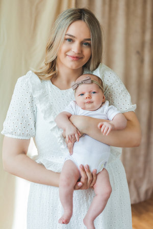 Young beautiful mother with blue eyes holds her little newborn daughter in her arms. motherhood. care. Baby. home.の写真素材
