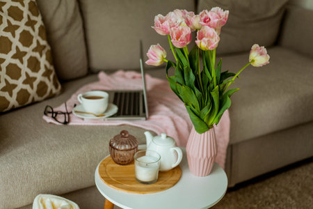 Home cozy office. Work at home. spring decor. Knitted blanket, bouquet of tulips, hot tea, laptop.の写真素材