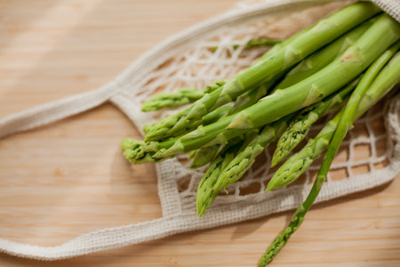 Bunch of green juicy asparagus in eco packaging on wooden board. Health food. health.の写真素材