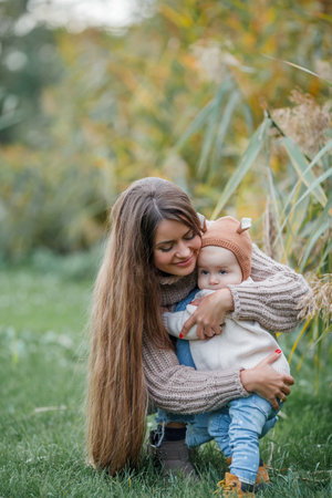 Beautiful young mother with her little daughter 2 years old in green park. happy family. Cosy. fall.の写真素材