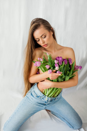Portrait of sexy beautiful young woman with long hair. Model with a bouquet of lilac tulips on white. holidays.の写真素材