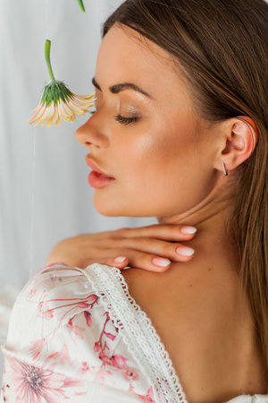 Portrait of young beautiful long-haired brown-eyed woman with pink gerbera on white background. Spring. holidays.の写真素材