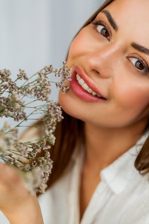 Portrait of beautiful young woman with long hair on white background with dried flowers.の写真素材